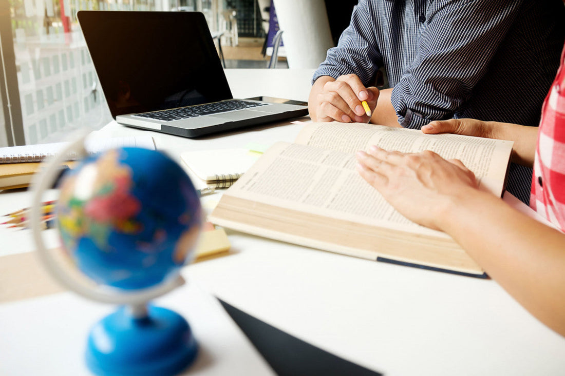 hand on a book with a globe symbol on front