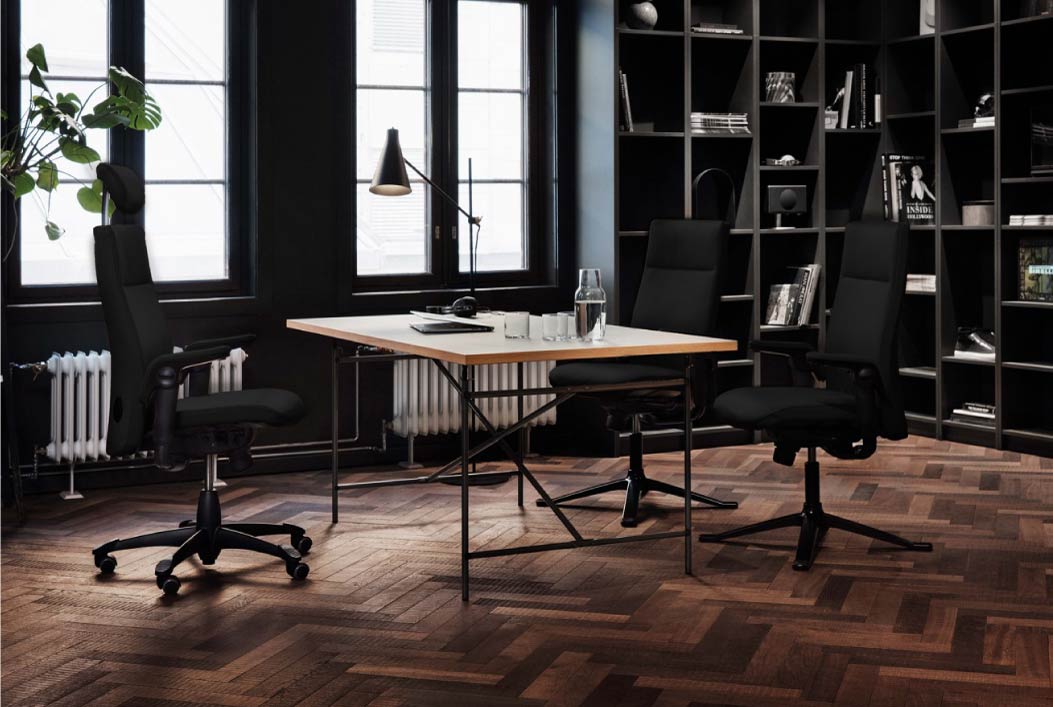 Modern office setup with desk, chairs, and bookshelves in a stylish room.
