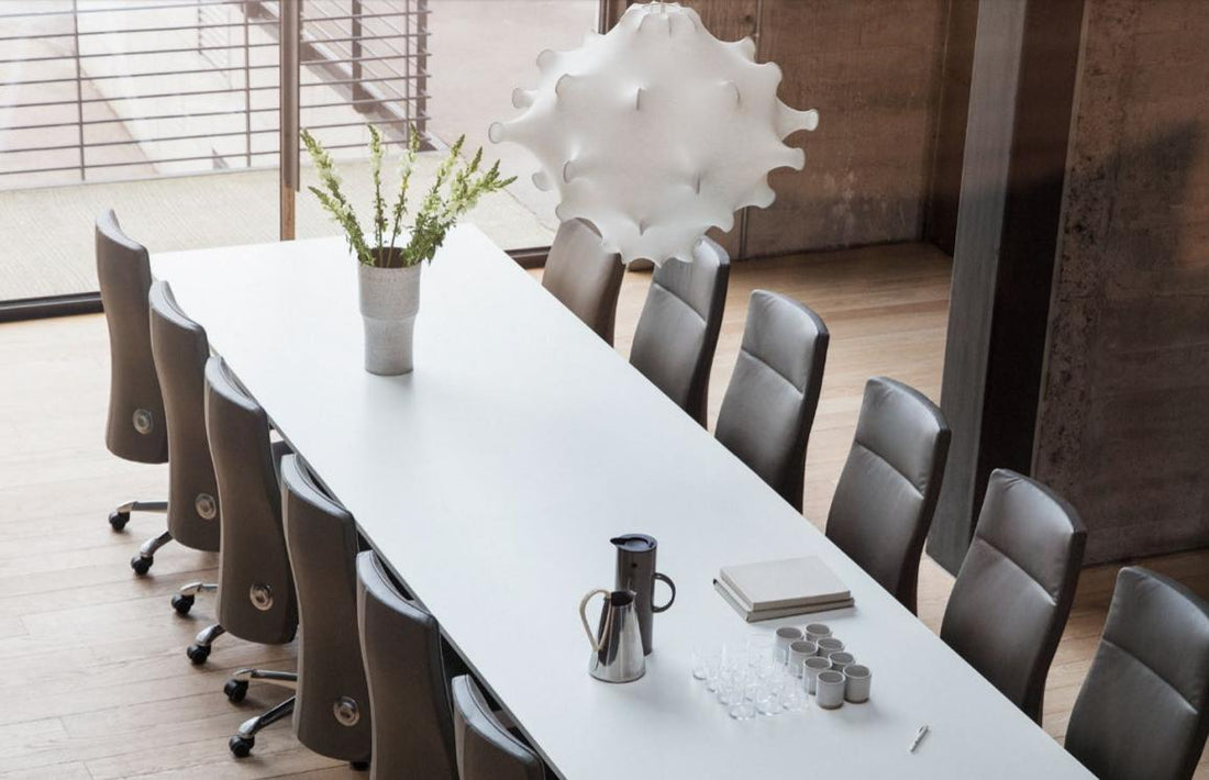 Modern conference room with a long white table and gray chairs.