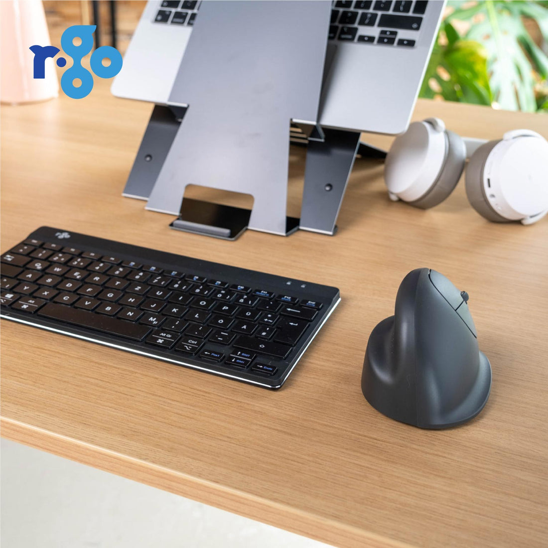 Keyboard and mouse setup on a desk with a laptop stand and office supplies.