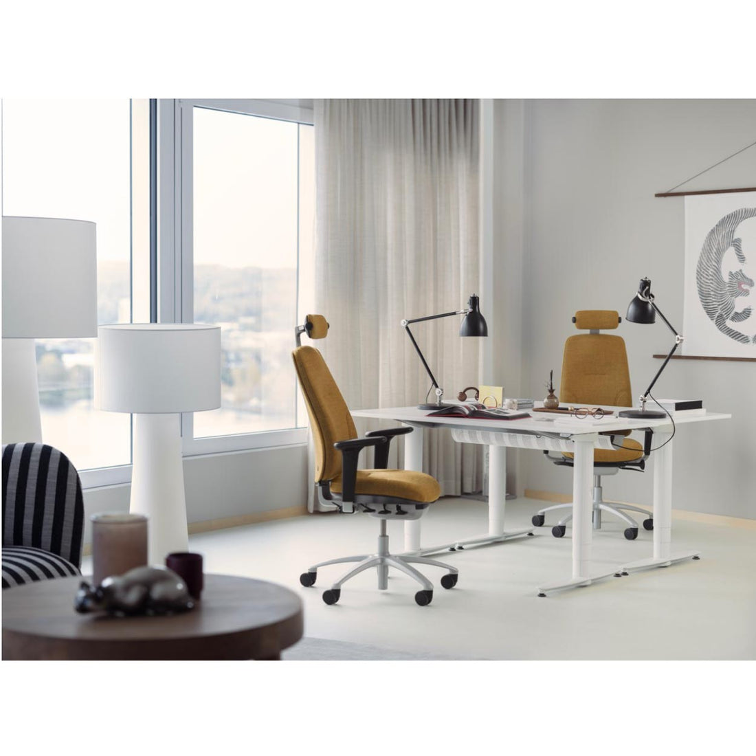 Modern office setup with a desk, chairs, and decorative items in a bright room.