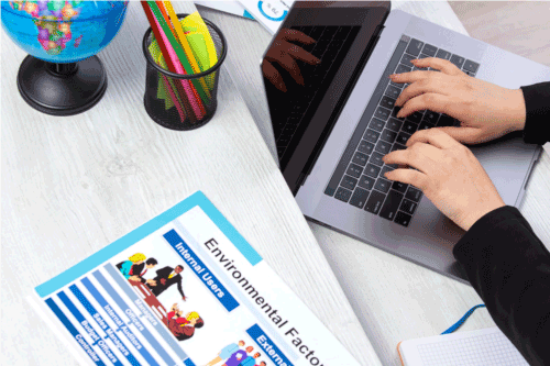 Person using a laptop with a document titled 'Environmental Factors' on a desk.