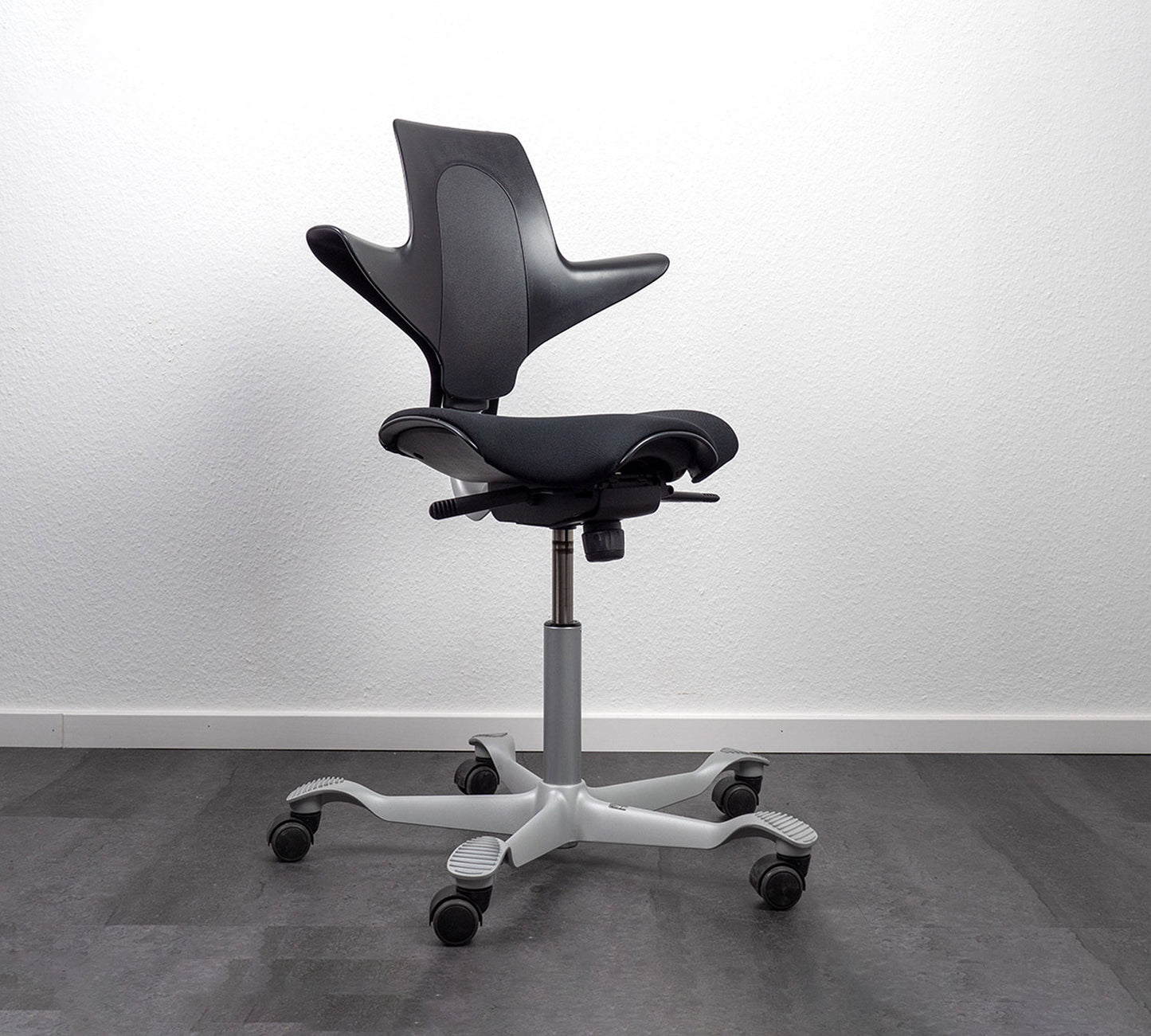Black office chair with white base on a gray floor and white wall background