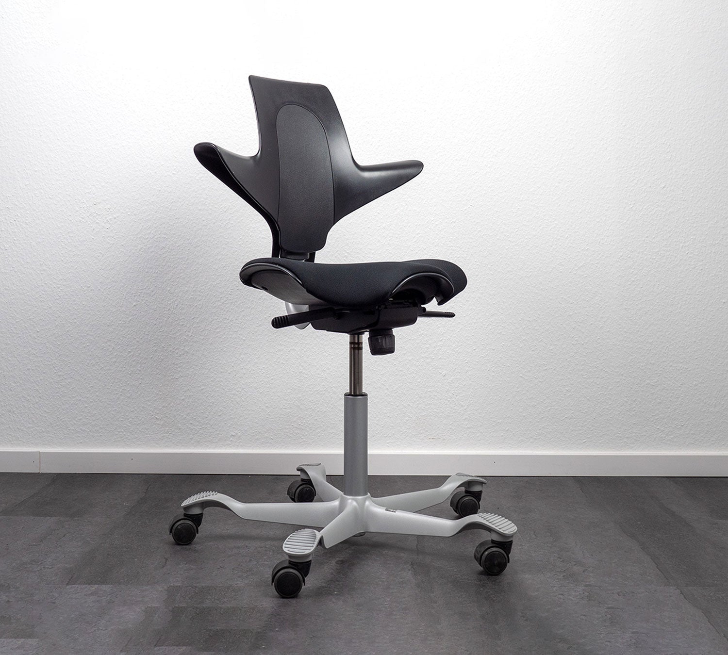 Black office chair with white base on a gray floor and white wall background