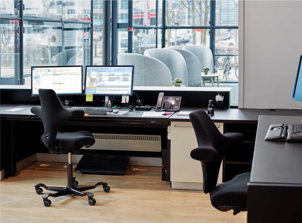 Modern office setup with desks, chairs, and computer monitors.