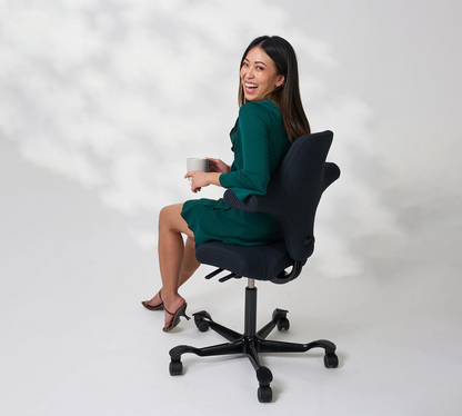 Woman sitting on a black office chair holding a cup against a white background