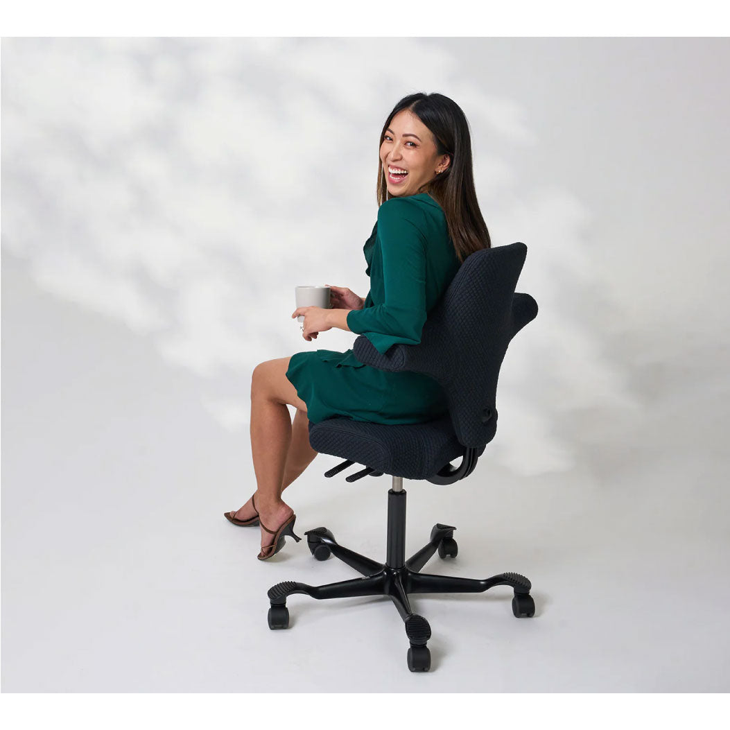 Woman sitting on a black office chair against a white background