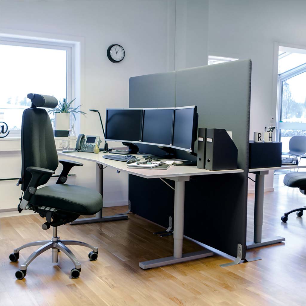 Modern office desk setup with ergonomic chair, computer monitors, and a glass partition.