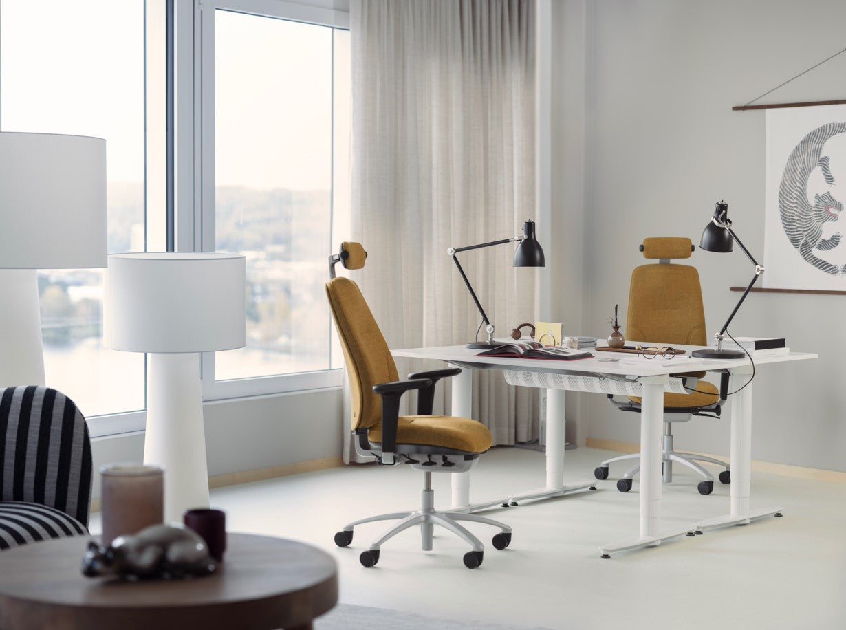 Modern office setup with a desk, chairs, and decorative items in a bright room.