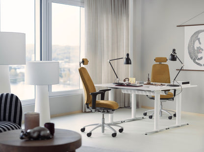 Modern office setup with a desk, chairs, and decorative items in a bright room.