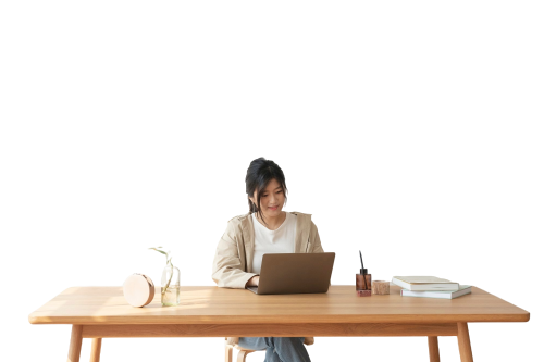 Woman sitting at a wooden desk using a laptop on a white background